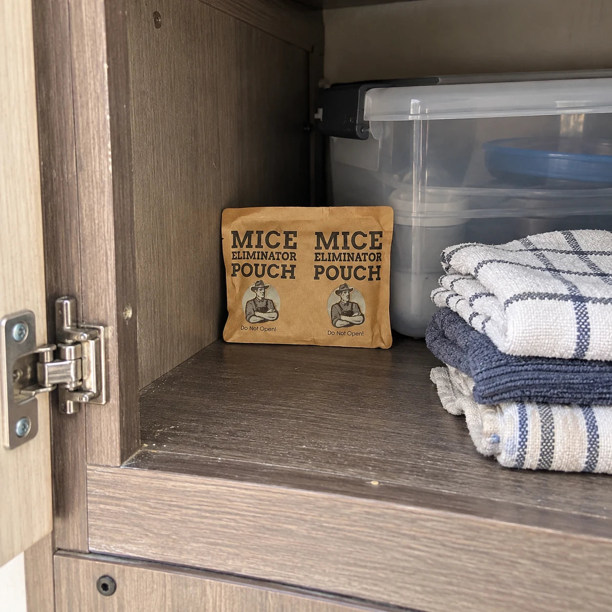 A pouch tucked inside a camper cabinet beside towels and a storage box